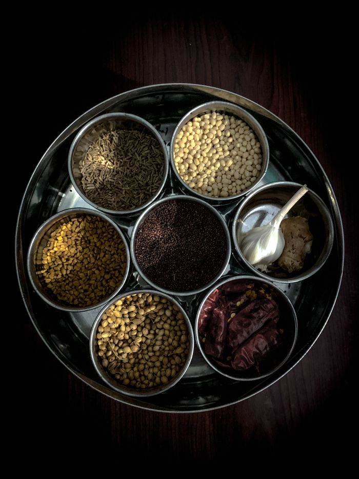 Top view of assorted Indian spices in a traditional container, highlighting vibrant textures.